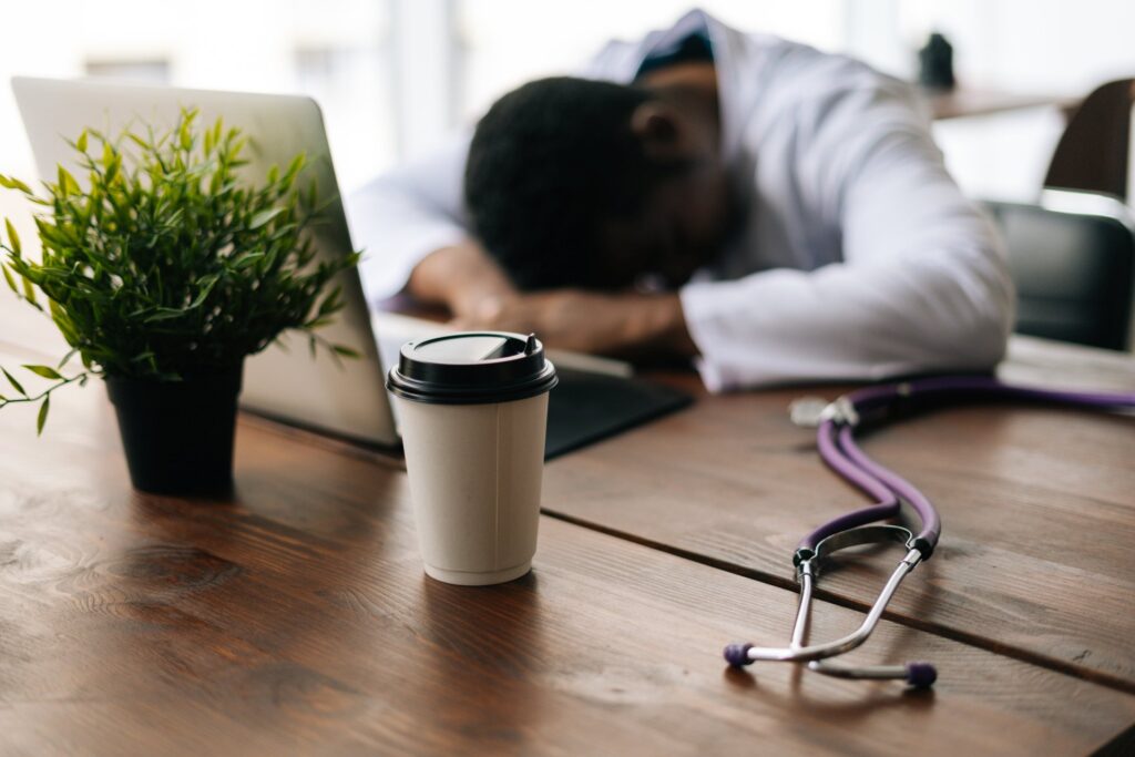 A doctor fall asleep besides a cup of coffee