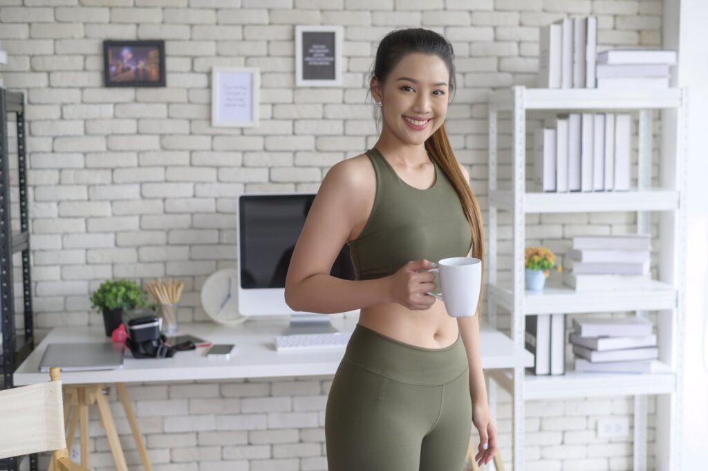 A young woman is having a cup of coffee before exercise
